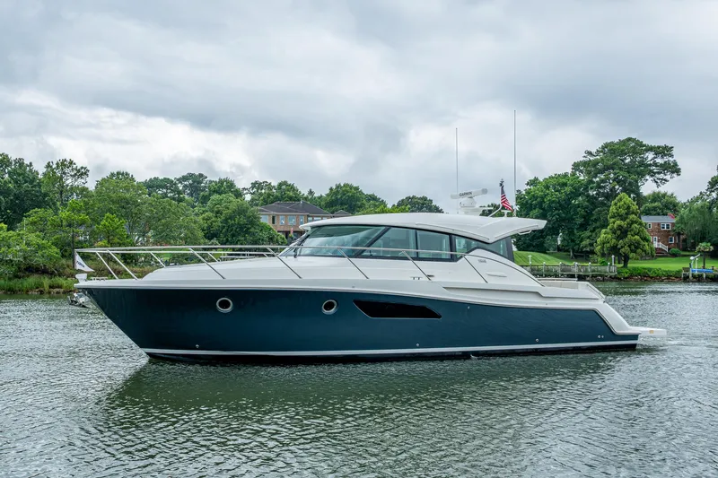 Slide: The Image of 2020 Tiara Yachts C44 Coupe on a serene waterway, surrounded by lush greenery. - 2