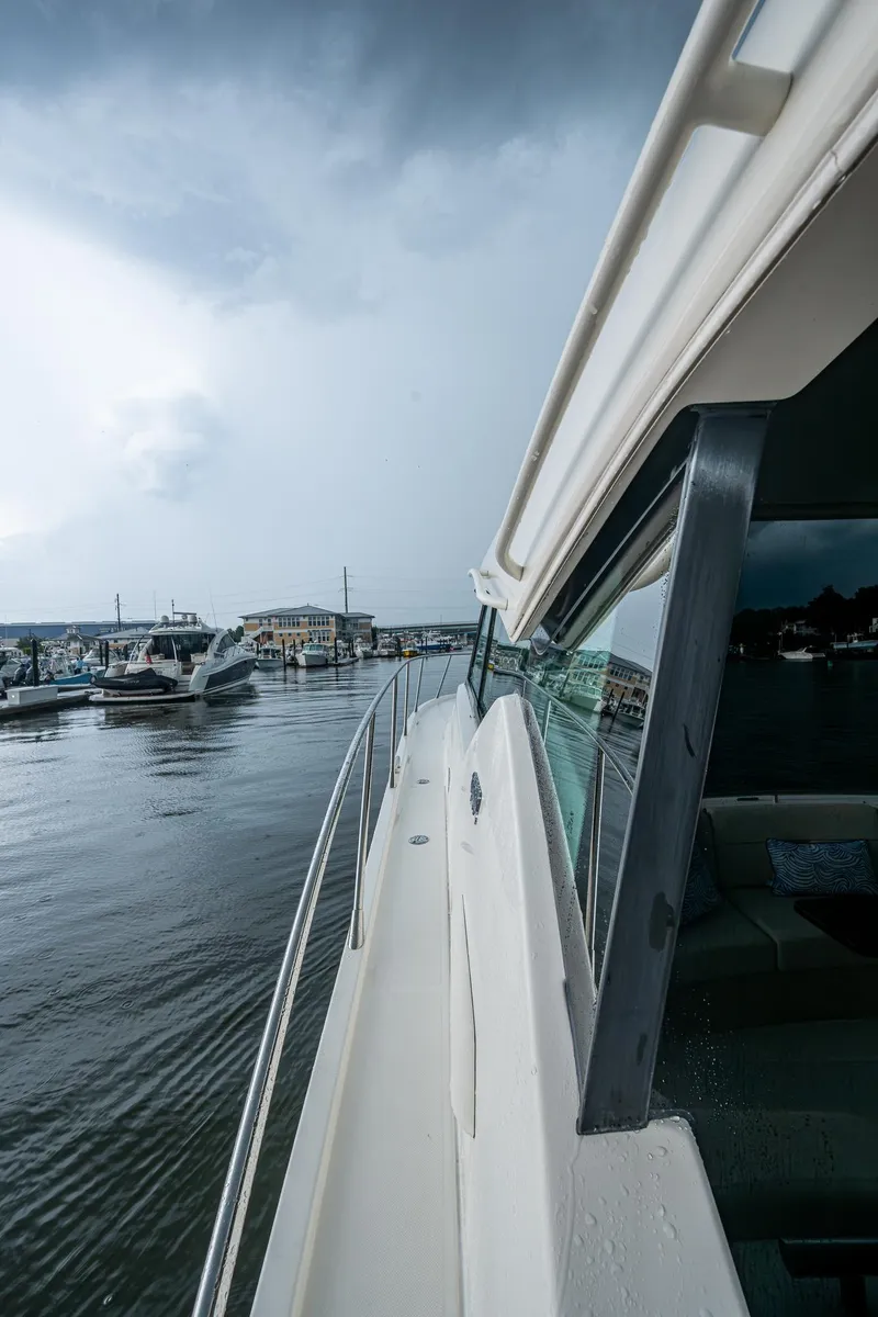 Slide: The Image of 2020 Tiara Yachts C44 Coupe on water, cloudy sky, marina view. - 23