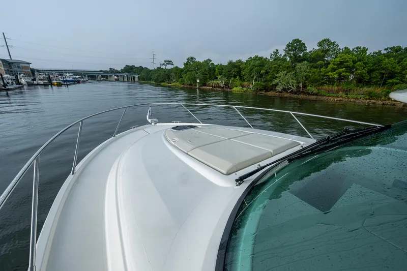 Slide: The Image of 2020 Tiara Yachts C44 Coupe cruising on a serene river near lush greenery. - 24