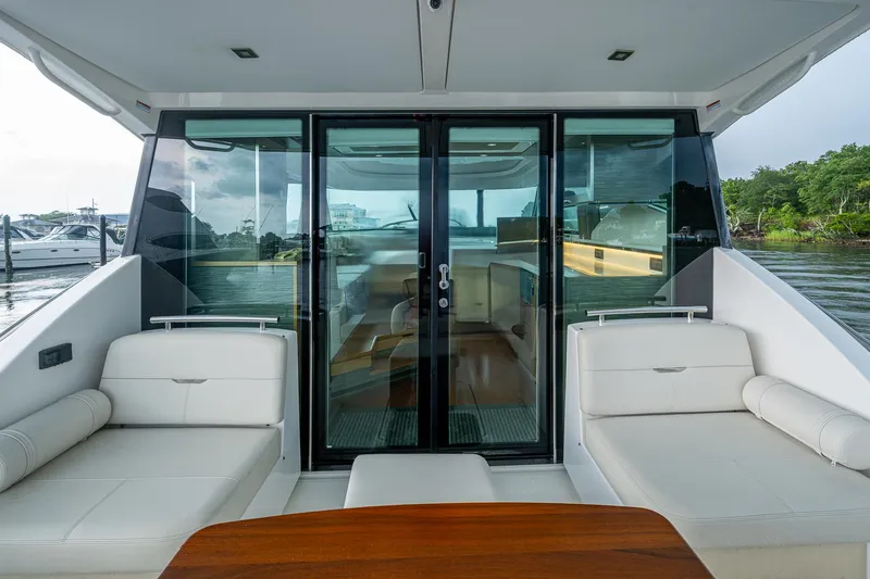 Slide: The Image of 2020 Tiara Yachts C44 Coupe interior with sleek seating and glass doors, dockside view. - 28