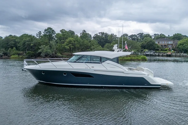 Slide: The Image of 2020 Tiara Yachts C44 Coupe on a serene waterway, surrounded by lush greenery. - 3