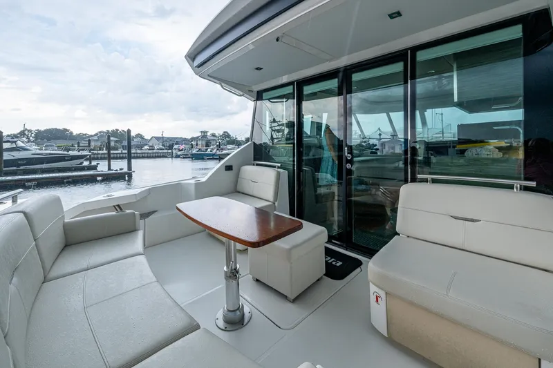 Slide: The Image of 2020 Tiara Yachts C44 Coupe with elegant seating and table, docked at marina. - 30