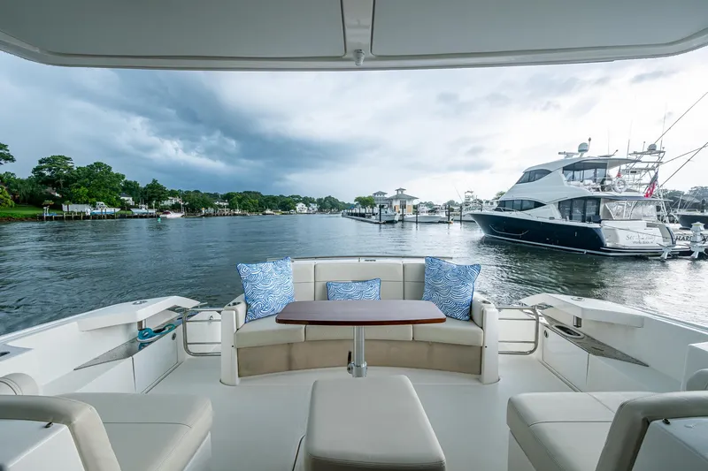 Slide: The Image of 2020 Tiara Yachts C44 Coupe interior with scenic marina view, featuring plush seating and cushions. - 34