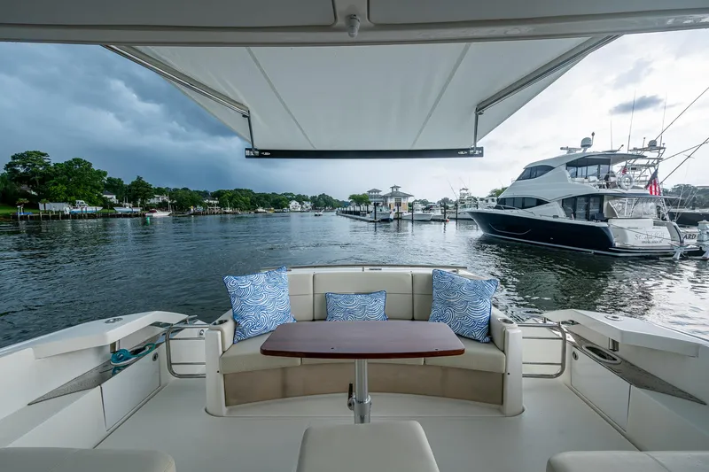 Slide: The Image of 2020 Tiara Yachts C44 Coupe with scenic marina view, featuring elegant seating and cushions. - 35