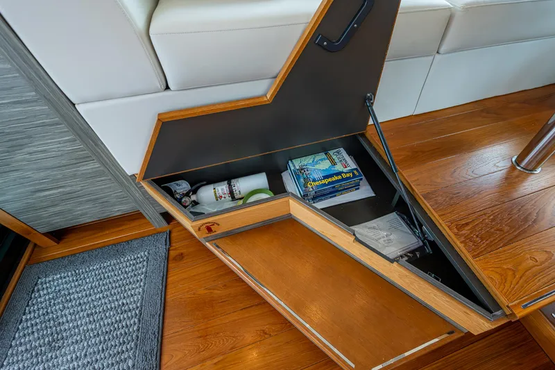 Slide: The Image of Open storage compartment in 2020 Tiara Yachts C44 Coupe with books and items inside. - 45
