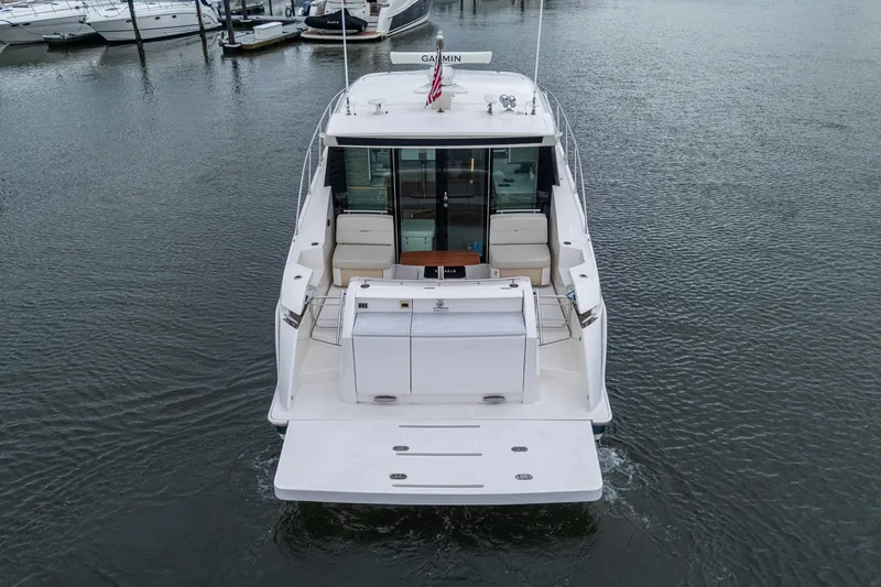 Slide: The Image of 2020 Tiara Yachts C44 Coupe docked, rear view showcasing spacious deck and seating area. - 9