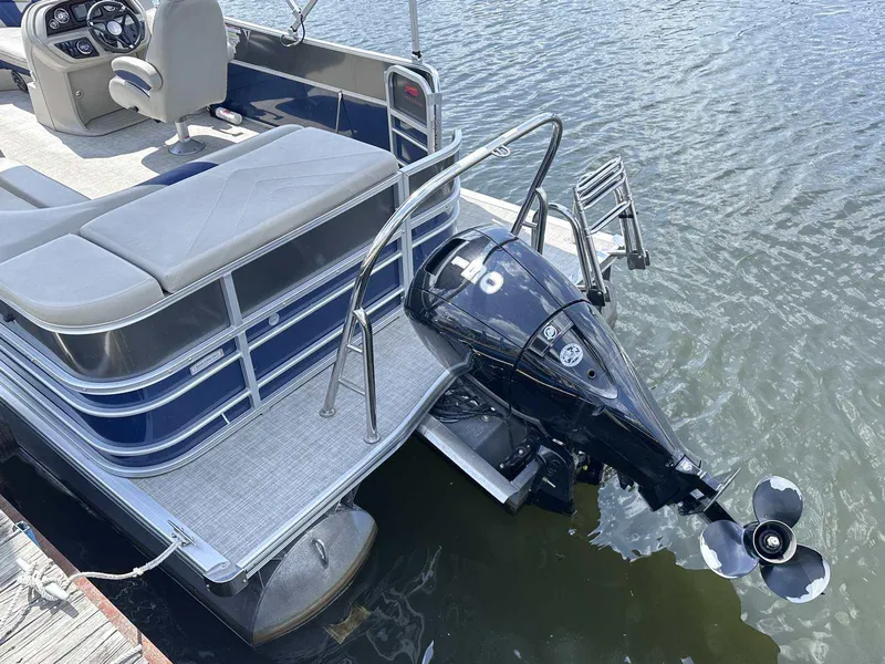 Slide: The Image of 2022 Trifecta 22 CL E pontoon boat with outboard motor on a calm lake. - 13