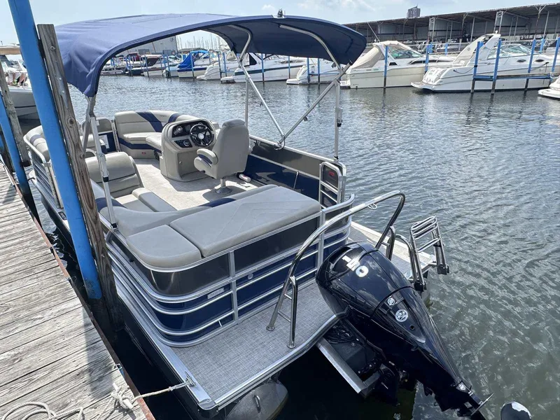 Slide: The Image of 2022 Trifecta 22 CL E pontoon boat docked at marina with blue canopy. - 14
