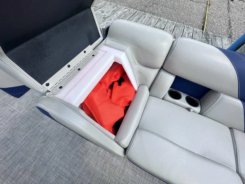 Slide: The Image of 2022 Trifecta 22 CL E boat seat storage with red life jacket and cup holders. - 4