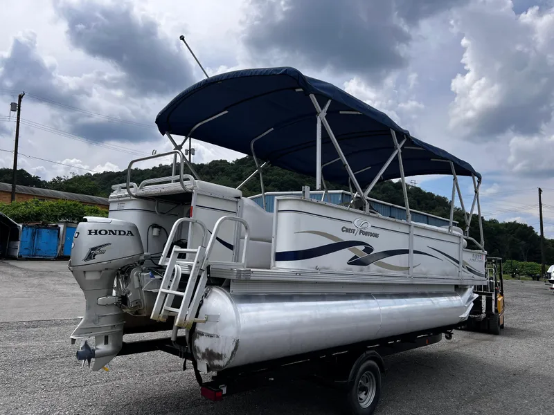 Slide: The Image of 2006 Crest II pontoon boat with Honda motor on trailer, under cloudy sky. - 3