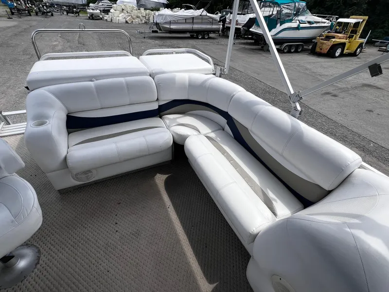 Slide: The Image of 2006 Crest II pontoon boat with white and blue seating, parked in a marina. - 8