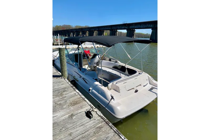 Slide: The Image of 2000 Rinker 272 Captiva Cuddy boat docked by a wooden pier under clear blue skies. - 14
