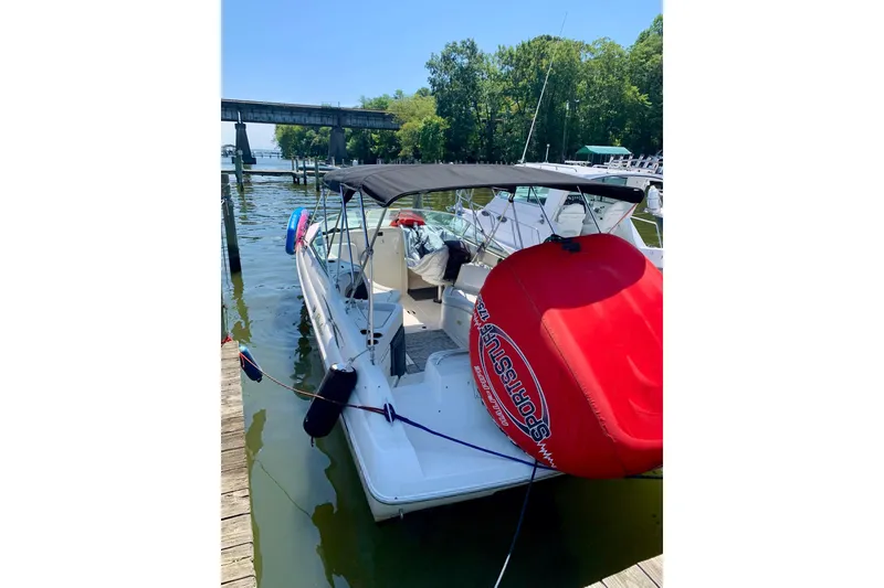 Slide: The Image of 2000 Rinker 272 Captiva Cuddy boat docked with red inflatable tube, sunny day. - 15
