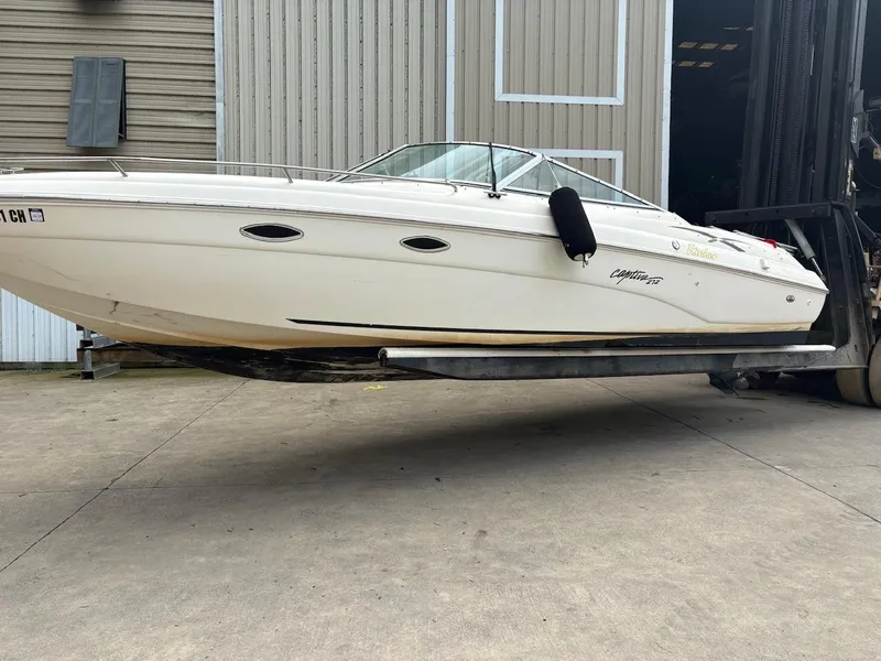 Slide: The Image of 2000 Rinker 272 Captiva Cuddy boat on forklift near warehouse. - 4