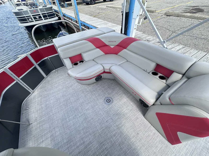 Slide: The Image of 2023 Trifecta 22 CLE 275 pontoon boat with red and gray seating, docked at marina. - 11