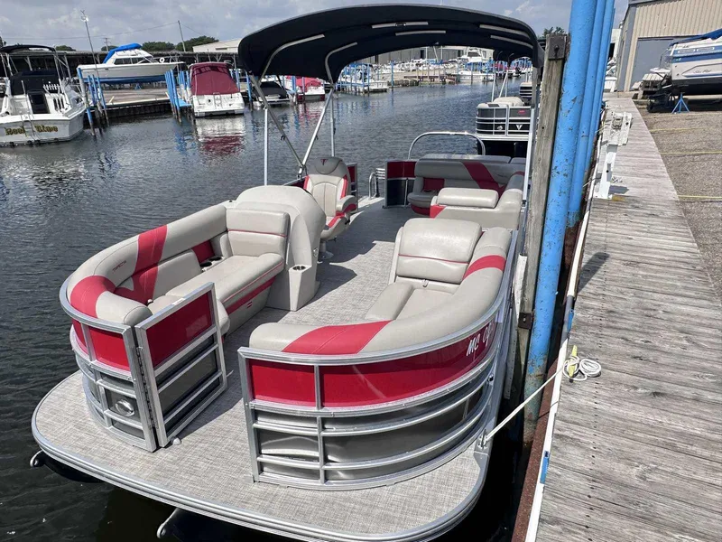 Slide: The Image of 2023 Trifecta 22 CLE 275 pontoon boat docked at marina, featuring red and gray seating. - 2