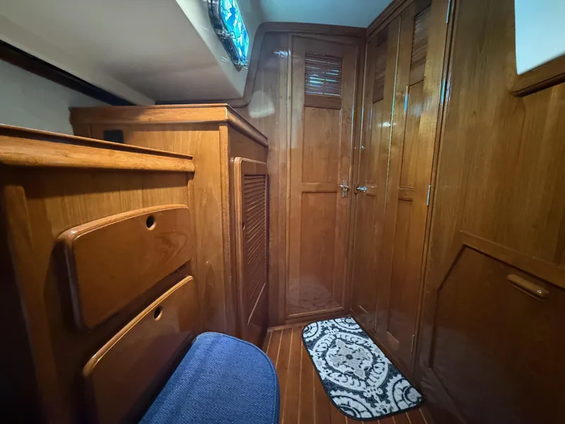 Slide: The Image of Interior of 1987 Island Packet 38 sailboat with wooden cabinetry and blue cushioned seating. - 21