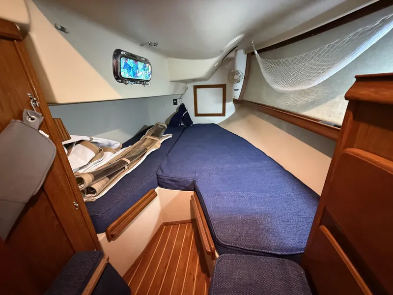 Slide: The Image of 1987 Island Packet 38 sailboat cabin with blue cushions and wooden interior. - 24