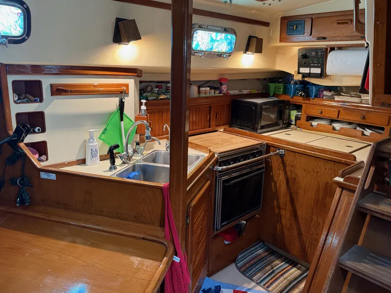Slide: The Image of Cozy 1987 Island Packet 38 yacht kitchen with wood cabinetry, sink, and appliances. - 29
