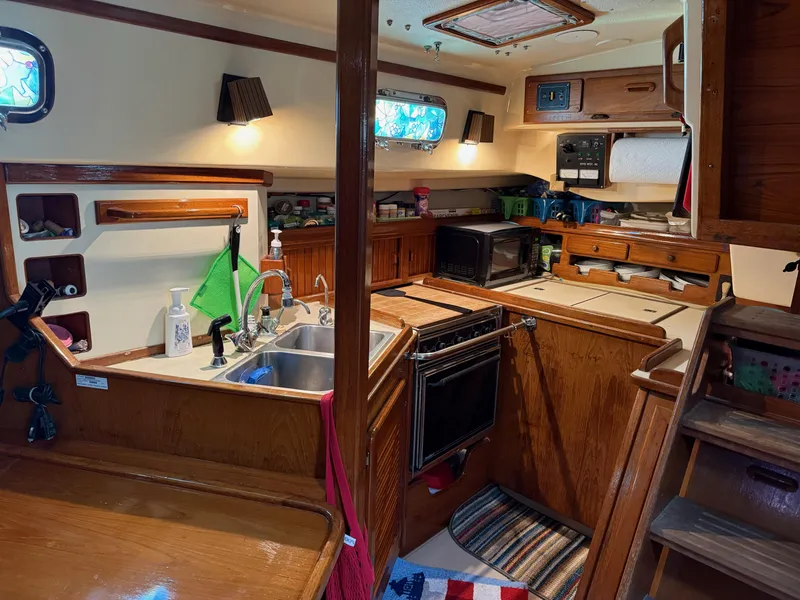 Slide: The Image of 1987 Island Packet 38 yacht interior kitchen with wooden cabinetry and modern appliances. - 31