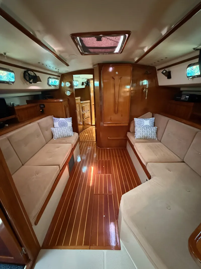 Slide: The Image of Interior of 1987 Island Packet 38 sailboat with wooden flooring and beige seating. - 33