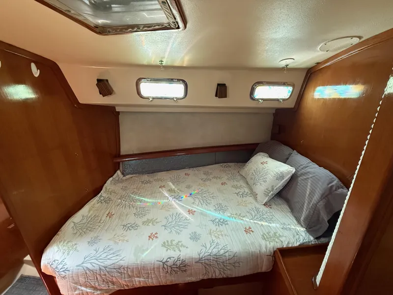 Slide: The Image of Cozy cabin interior of 1987 Island Packet 38 sailboat with comfortable bedding and wooden accents. - 38