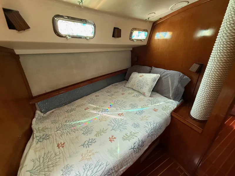 Slide: The Image of Cozy cabin interior of 1987 Island Packet 38 sailboat with nautical-themed bedding. - 39