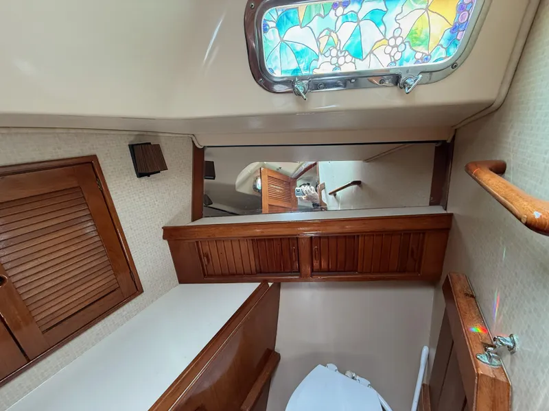Slide: The Image of Interior of 1987 Island Packet 38 sailboat bathroom with stained glass window and wooden cabinetry. - 42