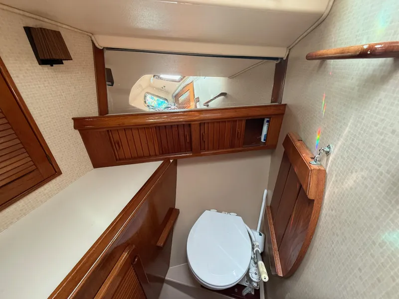 Slide: The Image of 1987 Island Packet 38 yacht bathroom with wooden cabinets and compact toilet. - 44