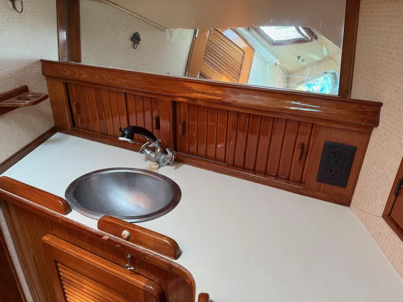 Slide: The Image of 1987 Island Packet 38 yacht bathroom with wooden cabinetry, stainless steel sink, and mirror. - 46
