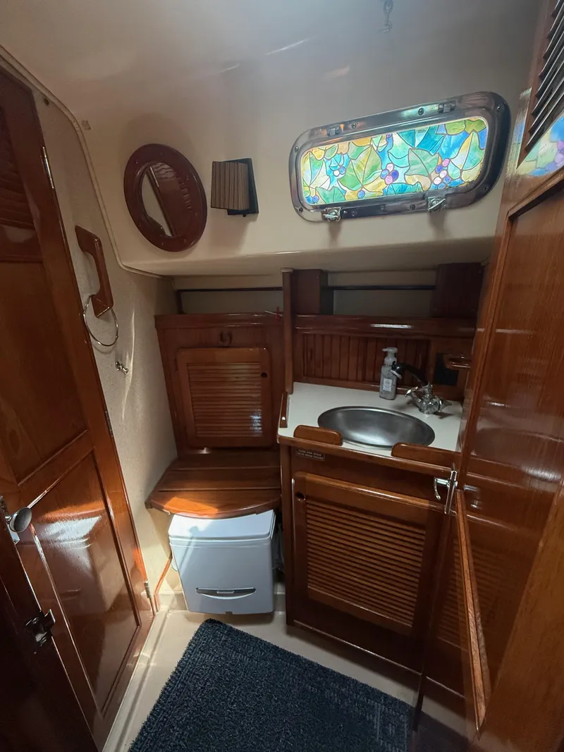 Slide: The Image of Interior of 1987 Island Packet 38 sailboat bathroom with wooden cabinetry and stained glass window. - 48
