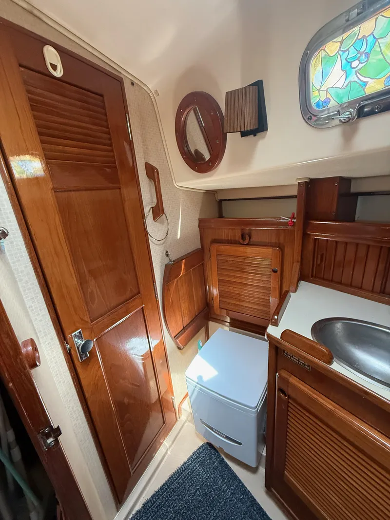 Slide: The Image of 1987 Island Packet 38 yacht interior with wooden cabinetry, sink, and stained glass window. - 49