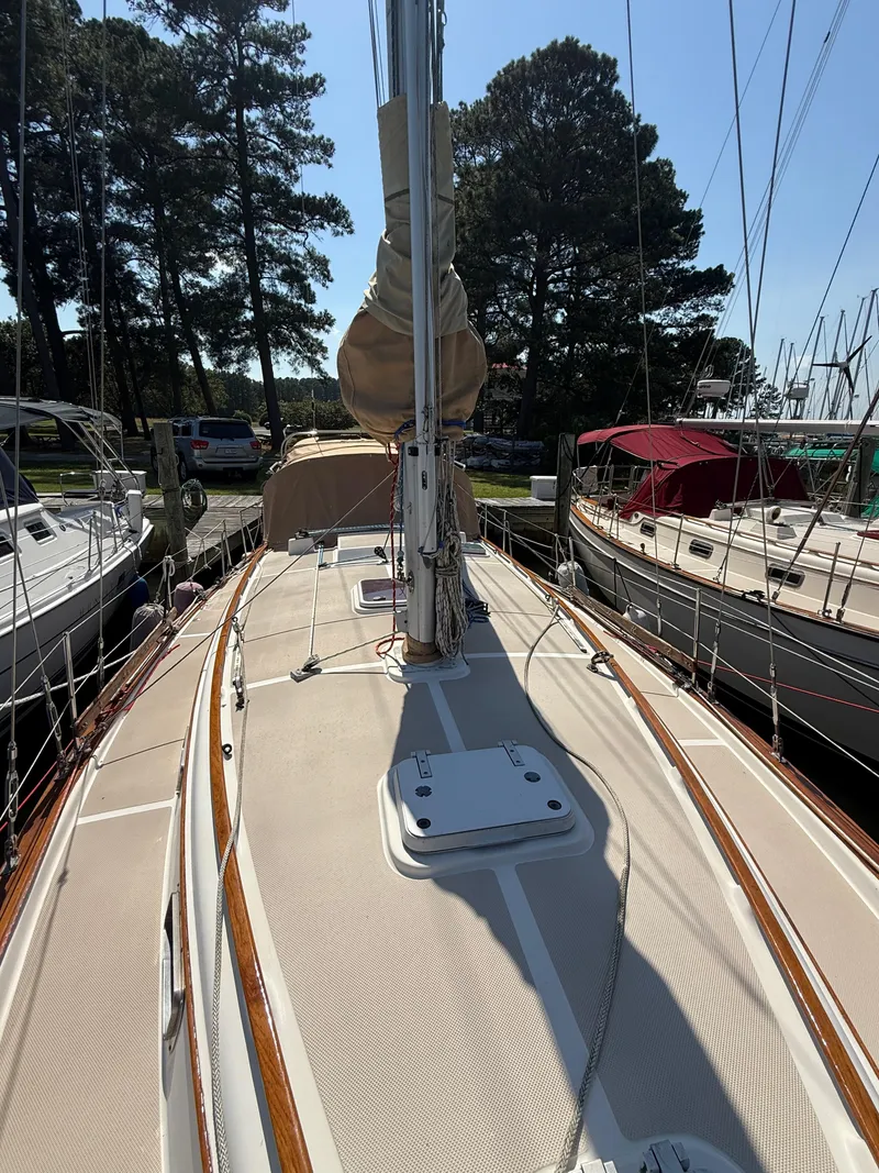Slide: The Image of 1987 Island Packet 38 sailboat deck with mast, docked among trees and other boats. - 7