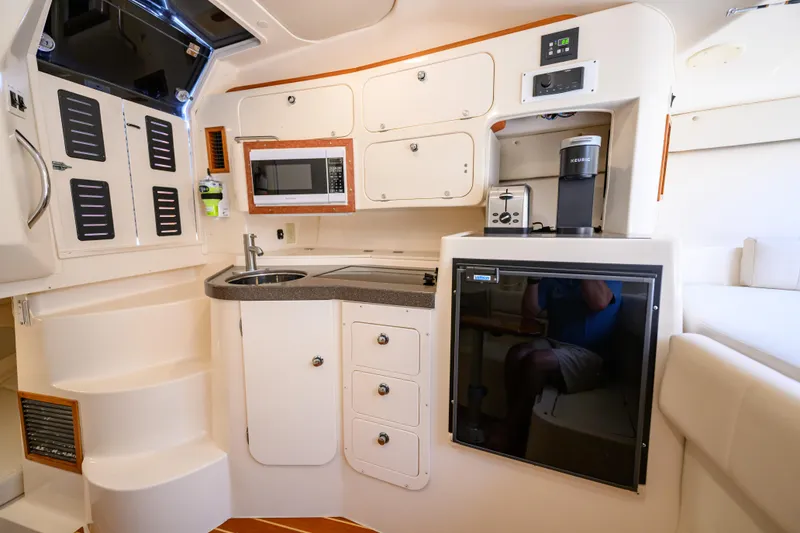 Slide: The Image of 2003 Grady-White Express 330 boat interior with kitchenette, featuring sink, microwave, and appliances. - 17