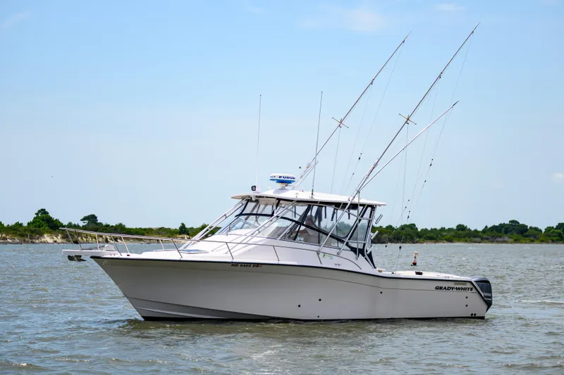 The Image of 2003 Grady-White Express 330 boat on water, clear sky, fishing rods visible. - 0