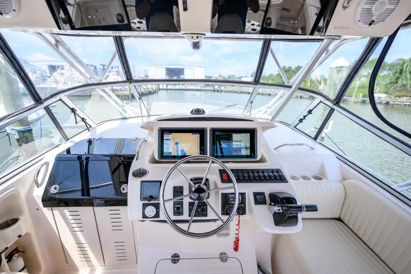 Slide: The Image of 2003 Grady-White Express 330 helm with navigation screens and steering wheel, docked at marina. - 13