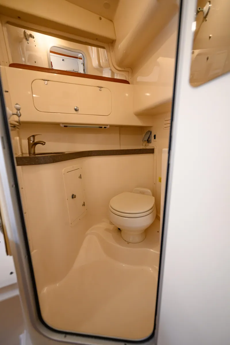 Slide: The Image of 2003 Grady-White Express 330 boat bathroom with sink, toilet, and storage cabinet. - 19