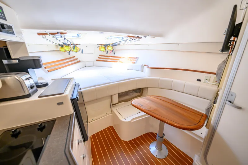Slide: The Image of 2003 Grady-White Express 330 cabin interior with kitchenette, seating, and fishing rods. - 15