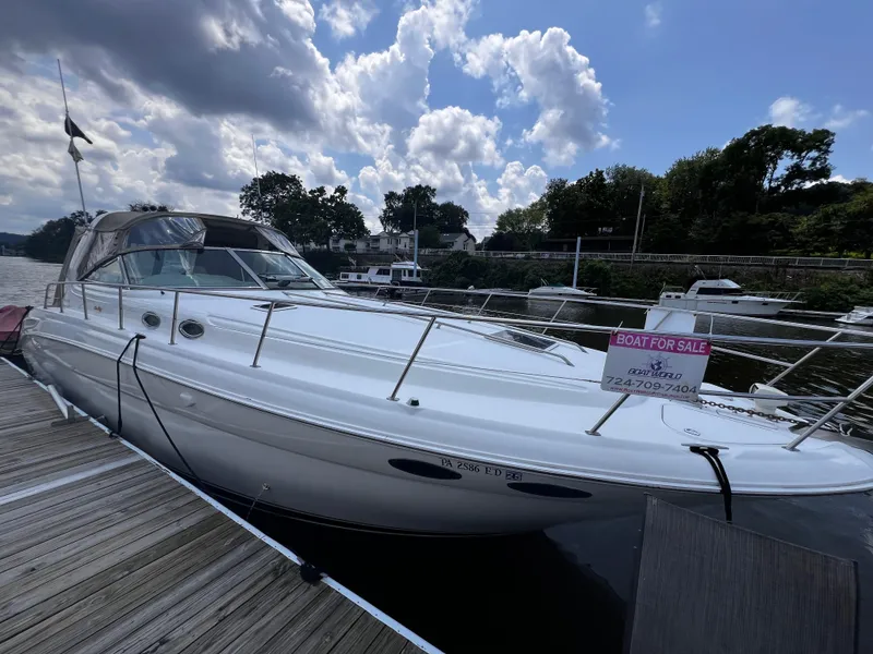 The Image of 2000 Sea Ray 380 Sundancer boat docked, for sale sign visible, under cloudy sky. - 0
