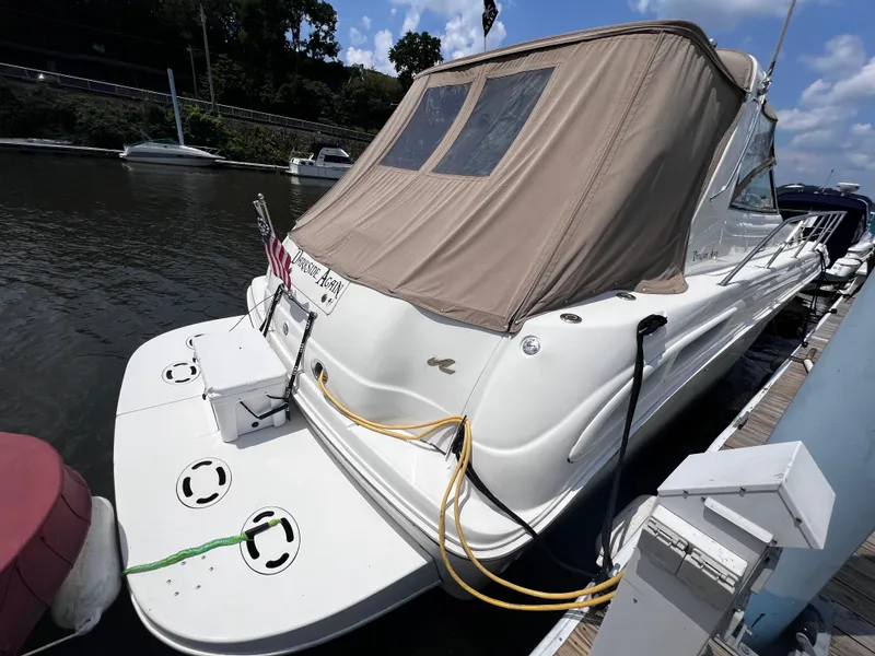 Slide: The Image of 2000 Sea Ray 380 Sundancer docked, featuring a beige canopy and sleek white design. - 1