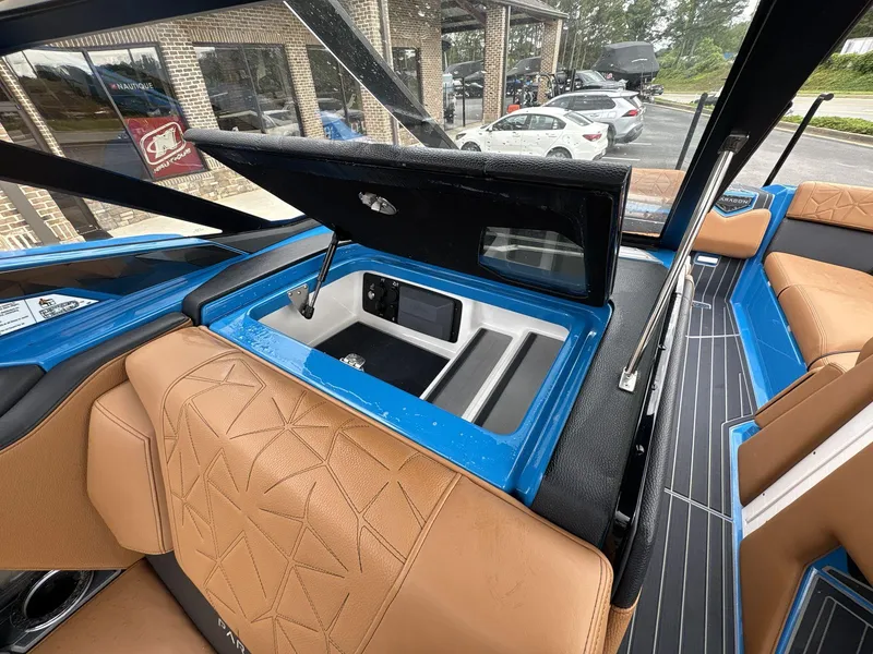 Slide: The Image of 2021 Nautique Super Air Nautique G23 Paragon interior with tan seats and open storage compartment. - 19