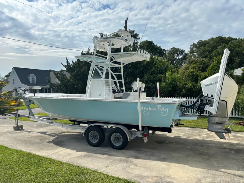 Slide: The Image of 2020 Canyon Bay 24H boat on trailer, parked in driveway, with outboard motor. - 24