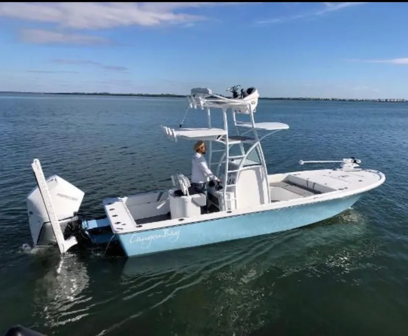 Slide: The Image of 2020 Canyon Bay 24H boat on calm water, clear sky, person steering. - 27
