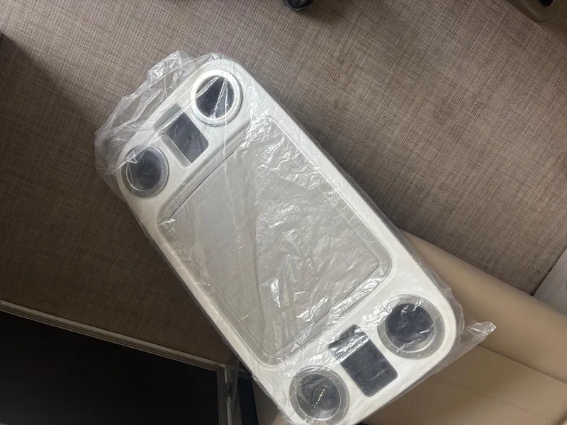 Slide: The Image of Plastic-wrapped table with cup holders on Sun Tracker PB 18 DLX, 2023 model. - 7