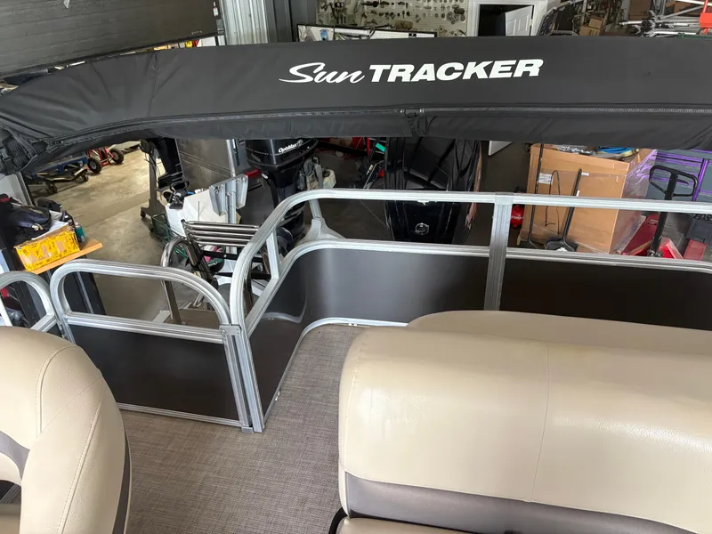 Slide: The Image of 2023 Sun Tracker PB 18 DLX pontoon boat interior with seating and canopy. - 8