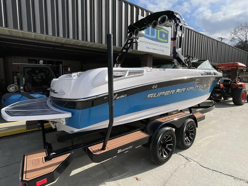 Slide: The Image of 2011 Nautique Super Air Nautique 230 boat on trailer, parked outside a building. - 14