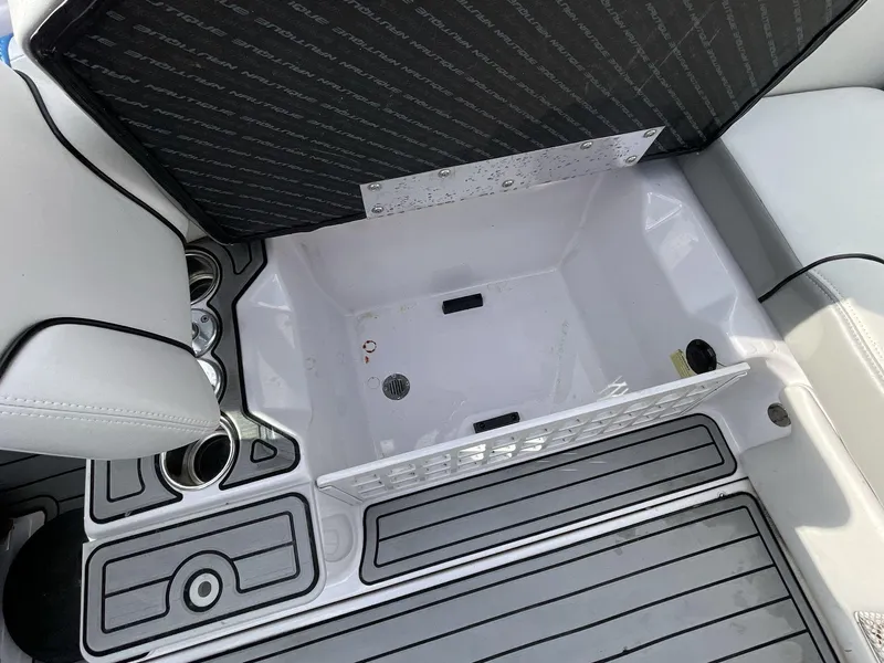 Slide: The Image of 2011 Nautique Super Air Nautique 230 storage compartment with open lid and cup holders. - 20