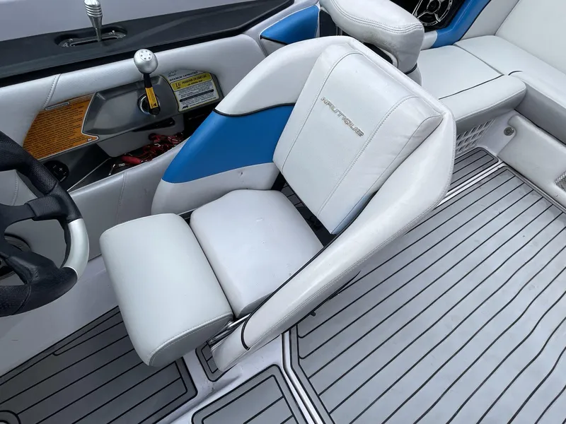 Slide: The Image of 2011 Nautique Super Air Nautique 230 interior with white and blue seating and steering wheel. - 29
