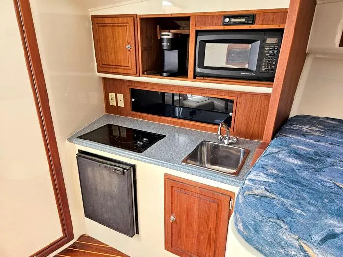Slide: The Image of Compact kitchen in 2001 Carolina Classic Express 35 boat with microwave, sink, and stove. - 20