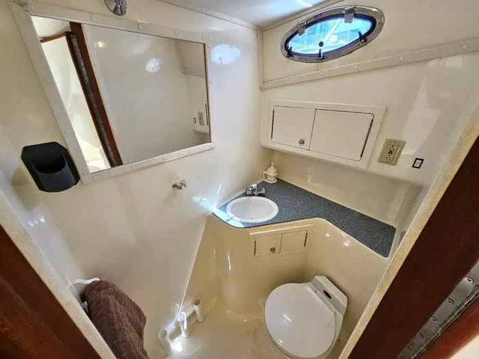 Slide: The Image of Compact bathroom in 2001 Carolina Classic Express 35 boat, featuring sink, toilet, and storage. - 22